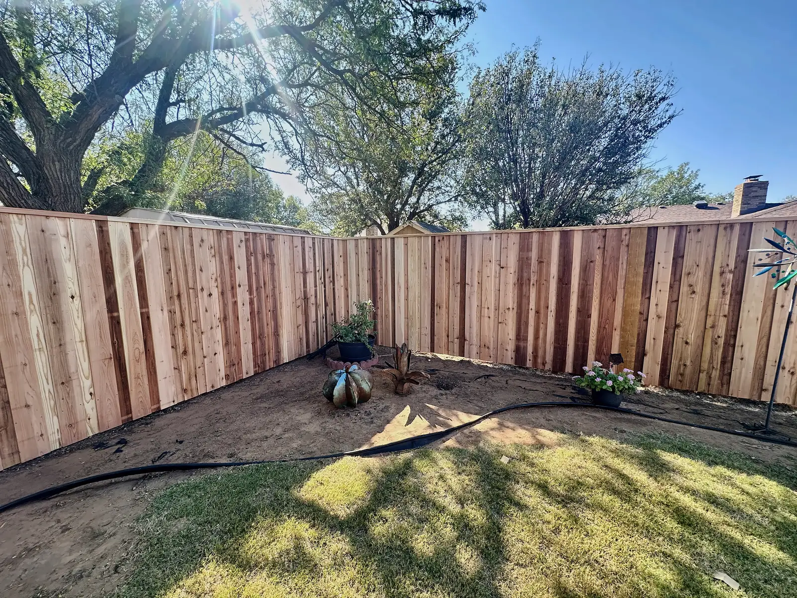 A completed cedar privacy fence corner in a Lubbock, TX backyard, installed by Hudson Fence Company