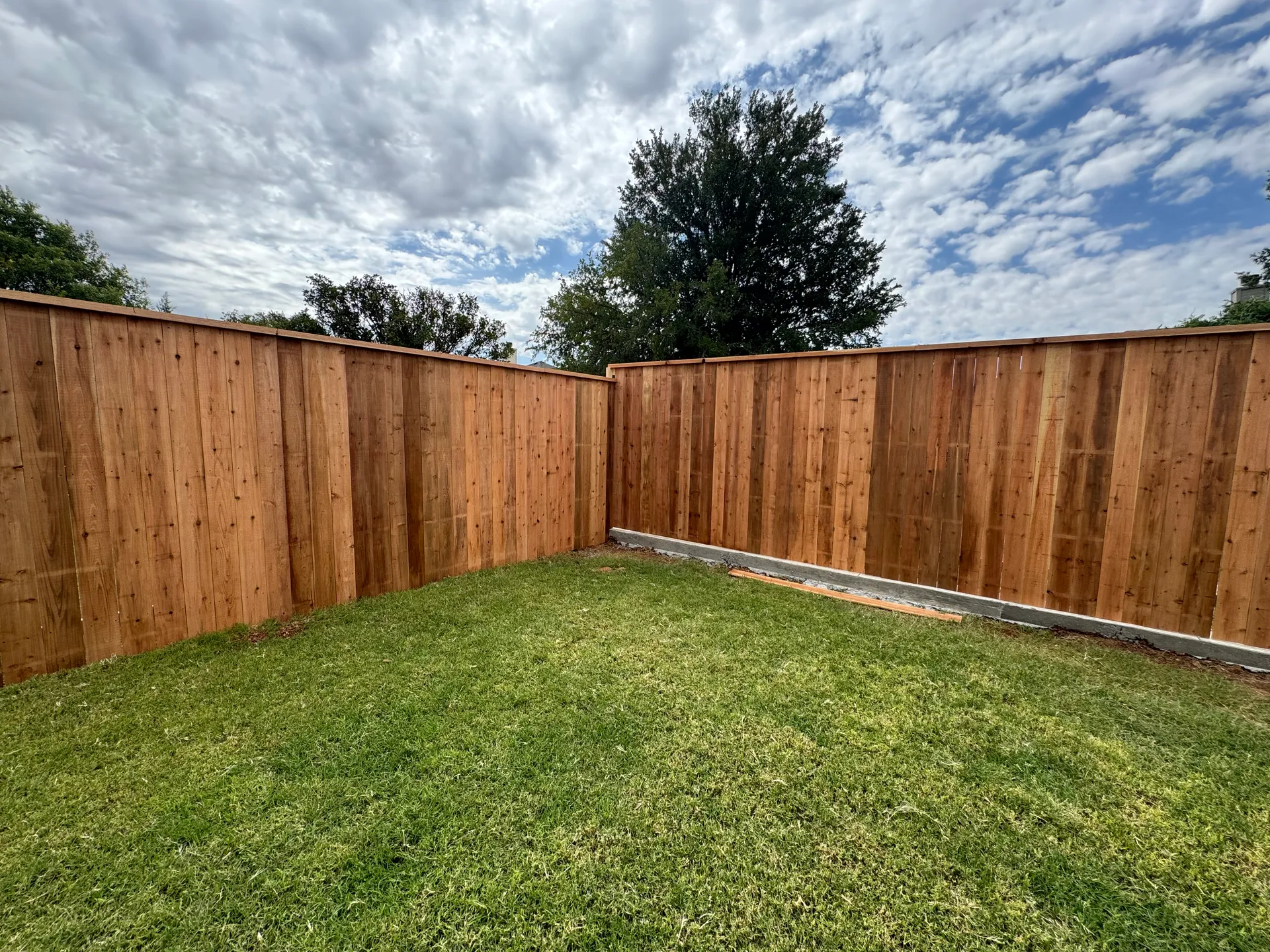 A completed cedar privacy fence corner in a Lubbock, TX backyard, installed by Hudson Fence Company